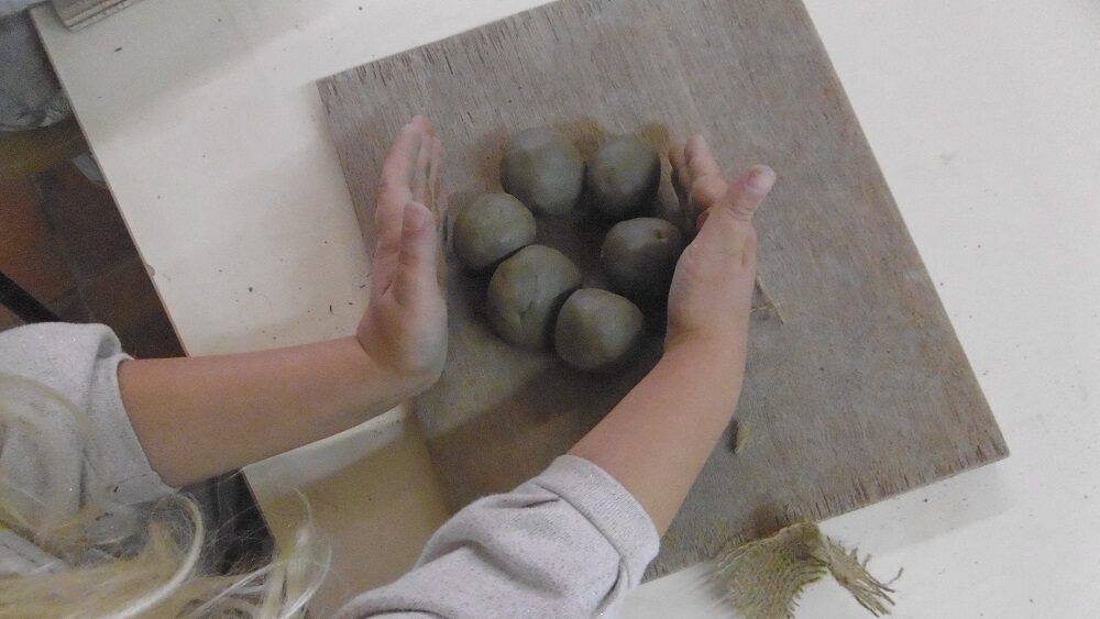 un enfant réalise des boules d'argile