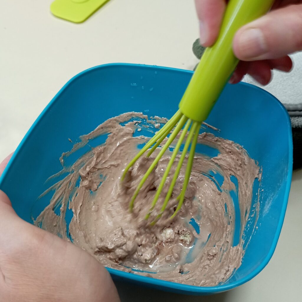 dans un récipient, un participant mélange l'argile et les différents ingrédients qui composent le masque