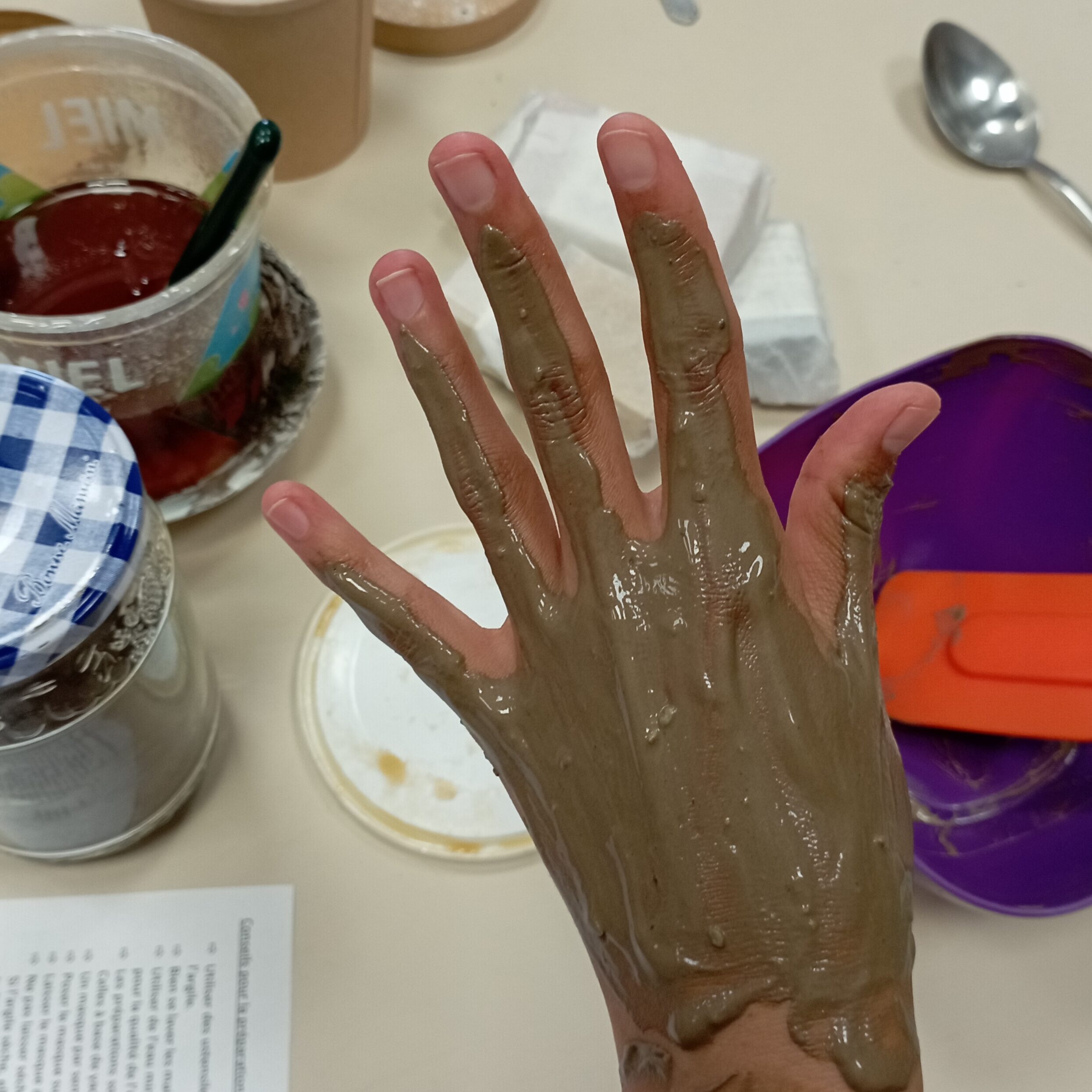 une participante pose un masque d'argile sur sa main